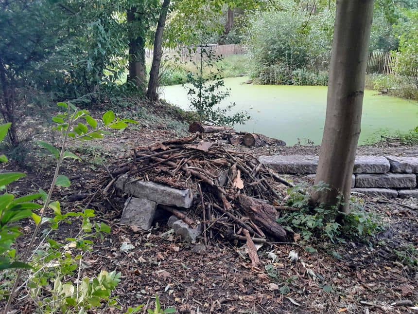 Foto van een schuilplaats gemaakt van stenen bedekt met takken.