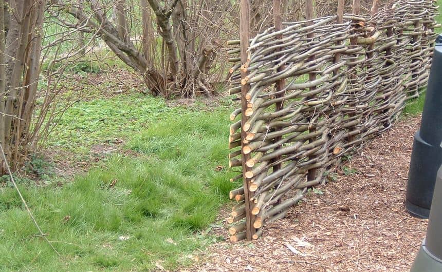 Foto van een hek gemaakt van dode wilgentakken gevlochten rond verticale palen
